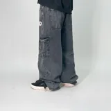 Pantalón jean negro de corte ultra baggy, con bolsillos cargo laterales y logo estampado en el muslo.