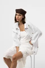 Camisa de lino blanca de corte relajado, con cuello clásico, mangas largas y delicados bordados florales en tono marrón.