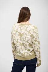 Buzo de tejido de punto con diseño floral en tonos beige y crema, de corte holgado, cuello redondo y mangas largas con puños acanalados.