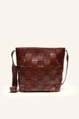 Cartera tipo bandolera de cuero marrón con diseño trenzado artesanal, formato balde y tira regulable para el hombro.