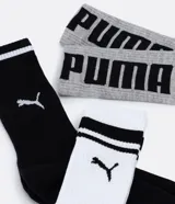 Kit de tres pares de medias deportivas Puma de caña larga. Un par es beige con dos rayas marrones y logo de Puma. Otro par es blanco liso. El tercer par es marrón oscuro con dos rayas blancas y logo de Puma. Todas están confeccionadas en algodón.