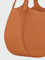 Cartera de mano Longchamp modelo Le Foulonné S, de diseño redondeado y estructura rígida, confeccionada en cuero con acabado liso y asa superior integrada.