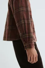 Camisa de franela de algodón suave con efecto lavado, color bordó con estampado a cuadros en tonos negros y amarillos. Presenta un corte relajado, cuello inglés, tapeta clásica de botones, un bolsillo superior abierto y canesú en la espalda. Tiene mangas largas con puños abotonados y un bajo ligeramente redondeado.