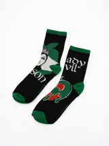 Pack de dos pares de medias de caña media, color negro con detalles en verde. Presentan estampados temáticos de villanos, incluyendo el rostro de la Reina Malvada y una manzana envenenada, con inscripciones alusivas.