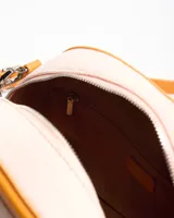 Cartera tipo baúl color tostado con cuerpo de lona y detalles en cuero sintético, asas de mano y correa larga regulable extraíble.