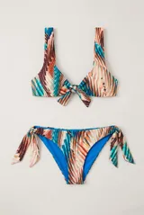 Conjunto de bikini con corpiño de tirantes anchos y nudo frontal, y bombacha semivedetina con lazos ajustables en los laterales. Presenta diseño estampado multicolor con predominio de tonos azules, naranjas y blancos, y revés en color azul.