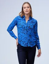 Camisa de gasa estampada con flores negras sobre fondo azul. Cuello con solapa y abertura central con botones.