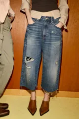 Bermuda tipo jorts de tiro medio confeccionada en denim azul con efecto lavado. Presenta diseño de cinco bolsillos, roturas decorativas y ruedo desflecado.