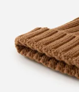 Gorro de punto texturizado color beige con vuelta y pompón de pelo sintético en la parte superior.