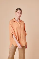 Camisa color naranja, de corte clásico y manga larga con presilla para sujetarla.