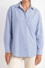 Camisa oversize de algodón con estampado de rayas verticales celestes y blancas, cuello clásico y mangas largas con puños abotonados.
