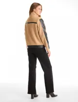 Campera de corderito sintético color beige con paneles y detalles en cuero sintético negro. Presenta cuello alto con tira y hebilla metálica, cierre frontal metálico y mangas largas con paneles de cuero sintético.