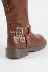 Botas de caña media color marrón, confeccionadas en cuero sintético, con suela de caucho y diseño decorado con múltiples hebillas metálicas ajustables.