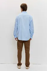 Camisa celeste de manga larga con cuello camisero abotonado y cierre frontal con botones.