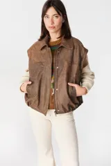 Campera de cuero estilo bomber con acabado desgastado, cuello clásico, cierre frontal oculto y mangas desmontables que permiten convertirla en chaleco.