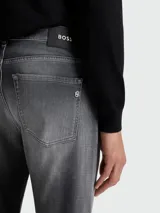 Jean de corte slim fit en denim gris con efecto lavado degradado. Cuenta con cierre de botón y cremallera, cinco bolsillos tradicionales y costuras reforzadas.