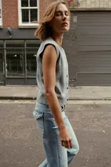 Chaleco de punto suave con cuello redondo, diseño sin mangas y cierre frontal con botones. Presenta terminaciones en rib en el cuello, sisas y ruedo.