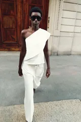 Top blanco de tejido de punto elástico, con escote asimétrico y una manga corta.