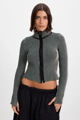 Campera corta de tejido de punto acanalado con diseño de rayas verticales en dos tonos. Presenta cuello alto y cierre frontal completo con borde en color negro.