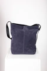 Bolso tipo tote de cuero gamuzado color marrón, con correa de hombro de cuero negro y hebilla metálica. Diseño minimalista y funcional. Confeccionado a mano en Uruguay.