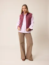 Camisa de manga larga con cuello clásico y cierre frontal de botones, confeccionada en tela de algodón con diseño de rayas verticales finas en color rosado y blanco. Presenta un bolsillo frontal en el pecho con detalle de etiqueta pequeña.