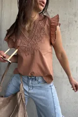 Musculosa de algodón color terracota, con escote en V y cuello ribeteado con bordados en relieve. Presenta mangas cortas con volados sutiles y diseño recto.