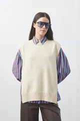 Chaleco tejido de punto con silueta relajada y diseño sin mangas. Presenta lazos laterales ajustables y cuello redondo.