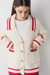 Cardigan de punto color chocolate con diseño de bloques de color y detalles a rayas en cuello, puños y ruedo. Presenta cierre frontal con botones, cuello tipo polo y dos bolsillos delanteros.