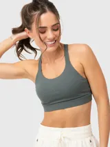 Top deportivo de alto soporte color verde militar, con diseño de costuras cruzadas en el frente y espalda estilo nadadora con tirantes ajustables. Incluye almohadillas removibles.