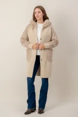 Tapado largo de textura combinada, con cuerpo de punto suave y mangas y bolsillos de tejido tipo corderito. Presenta cuello con capucha de piel sintética y cierre frontal con botones.