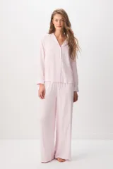 Pijama rosado de 100% viscosa con diseño a rayas sutiles, compuesto por una camisa de manga larga con cuello solapa y botones delanteros, y un pantalón largo de corte holgado con cintura elástica y cordón ajustable. Presenta un pequeño detalle bordado de corazón rojo en el pecho de la camisa.