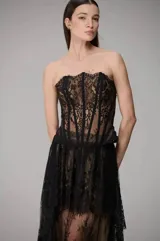 Corset de encaje negro con diseño strapless y varillas estructuradas visibles.
