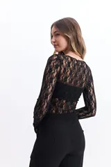 Remera negra de encaje floral con mangas largas, cuello redondo y corte ajustado. Incluye una capa interior opaca en el área del busto.