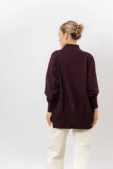 Sweater de tejido de punto color beige, con cuello alto, hombros caídos, mangas largas con puños acanalados y tajos laterales en el ruedo.