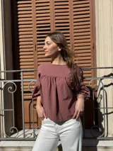 Blusa color chocolate de diseño holgado, con cuello redondo, frunce frontal y mangas abullonadas con puños ajustados.