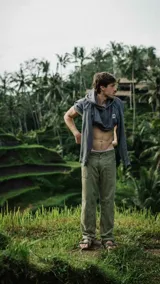 Canguro gris con capucha, cordones ajustables y bolsillos tipo canguro. Presenta un logo cuadrado con una "X" en el pecho.