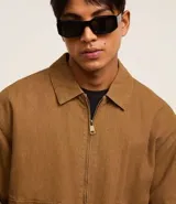 Campera bomber marrón de sarga de algodón, con cuello inglés, cierre frontal con cremallera, bolsillos cargo con botón y puños y cintura ajustados.