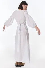 Vestido midi fucsia de lino, con escote en V, mangas largas abullonadas, lazos frontales y tajo lateral.