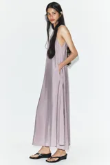 Vestido midi de corte fluido y diseño minimalista, con cuello redondo y mangas sisa. Presenta una abertura en la espalda con cierre y lazada ajustable.