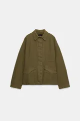 Chaqueta de estilo utilitario color verde militar, con cuello solapa, manga larga y cierre frontal con botones ocultos por solapa. Presenta bolsillos con solapa en la parte delantera y un bolsillo de plastrón en el pecho.
