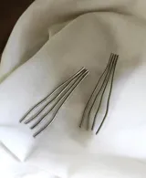 Aros colgantes plateados con forma de líneas onduladas.