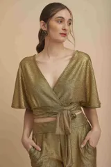 Top dorado de tejido brillante tipo lurex, cruzado con escote en V profundo, mangas cortas amplias y cintas para atar en la cintura.