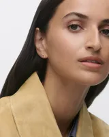 Aros pequeños de oro con forma de ángulo recto y detalle de circonitas blancas.