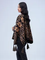 Poncho tejido con diseño tribal en blanco y negro, terminación con borlas.