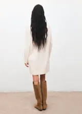 Vestido corto de punto color crudo, con cuello vuelto y mangas largas, de diseño recto y sin cierre.
