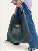 Bolso tote negro de cuero con doble asa al hombro color marrón.