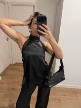 Top lencero negro de satén con cuello halter y detalles de encaje en los bordes.
