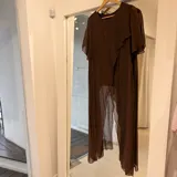 Blusa larga de gasa color marrón chocolate, con mangas cortas, cuello redondo y diseño asimétrico con volados.