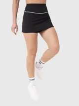 Falda deportiva negra con diseño de tiro alto y ribete blanco en la cintura. Incluye calza interna con bolsillo incorporado para mayor funcionalidad durante la actividad física.