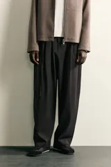 Pantalón de corte balloon fit confeccionado en tejido con viscosa. Presenta cintura ajustable con cinturón integrado, pliegues frontales, bolsillos laterales y bolsillos traseros de doble vivo. Cierre frontal con cremallera y botón.